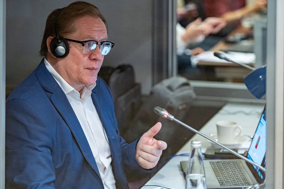 Viktor Kozyrev speaking into a booth microphone with headset